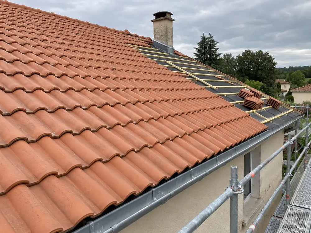 rénovation d’une couverture en tuiles avec une zone de toiture en cours de réfection